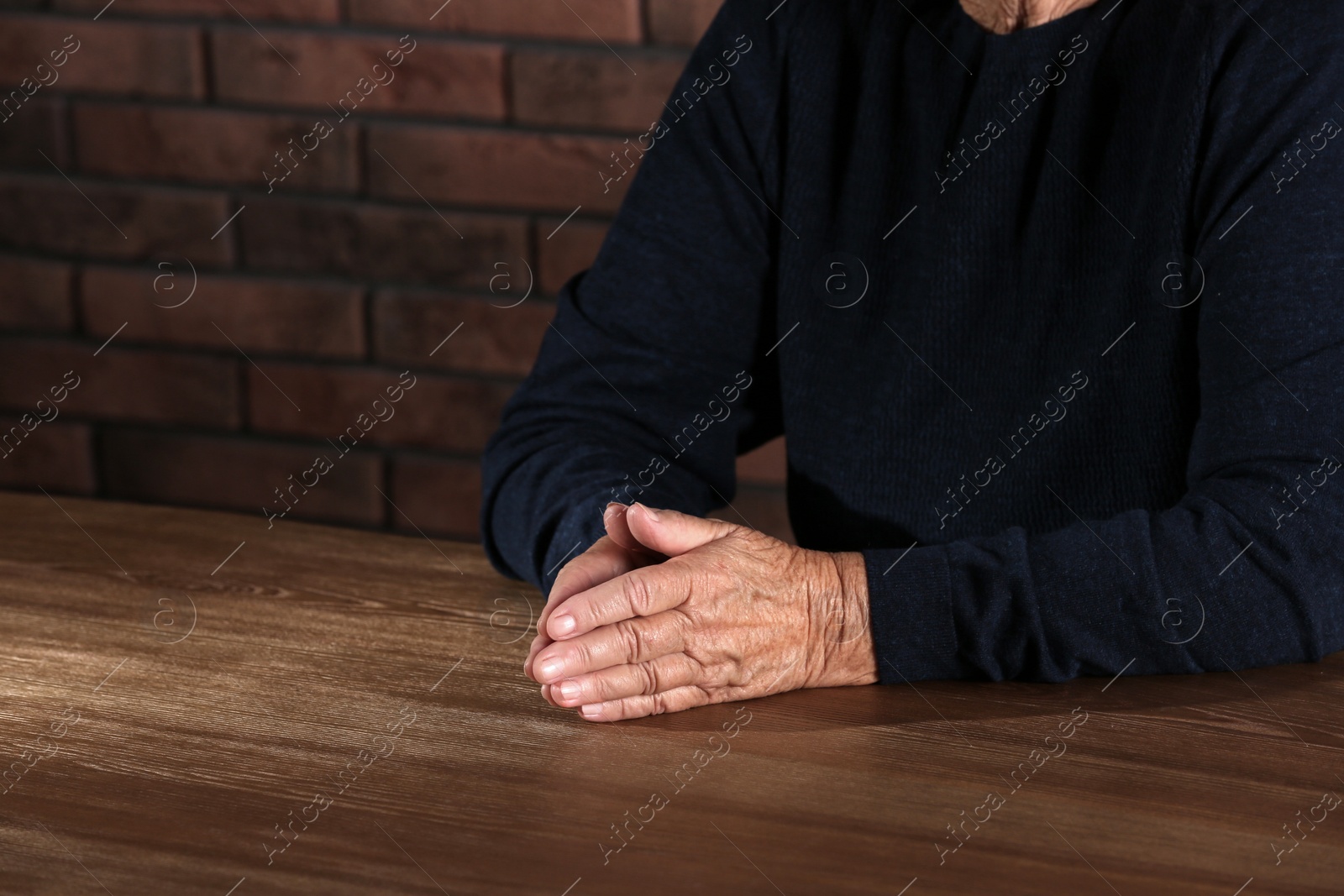 Photo of Poor elderly woman sitting at table, focus on hands