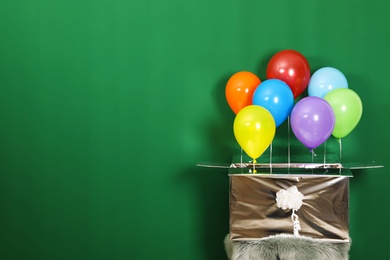 Gift box with bright air balloons on green background. Space for text