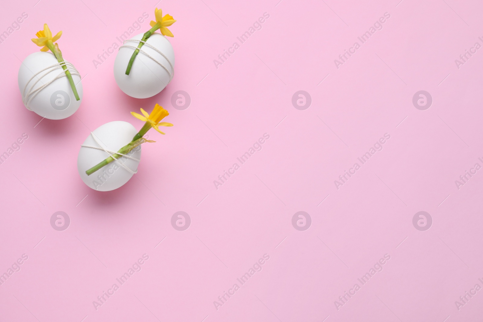 Photo of Easter eggs decorated with flowers on pink background, flat lay. Space for text