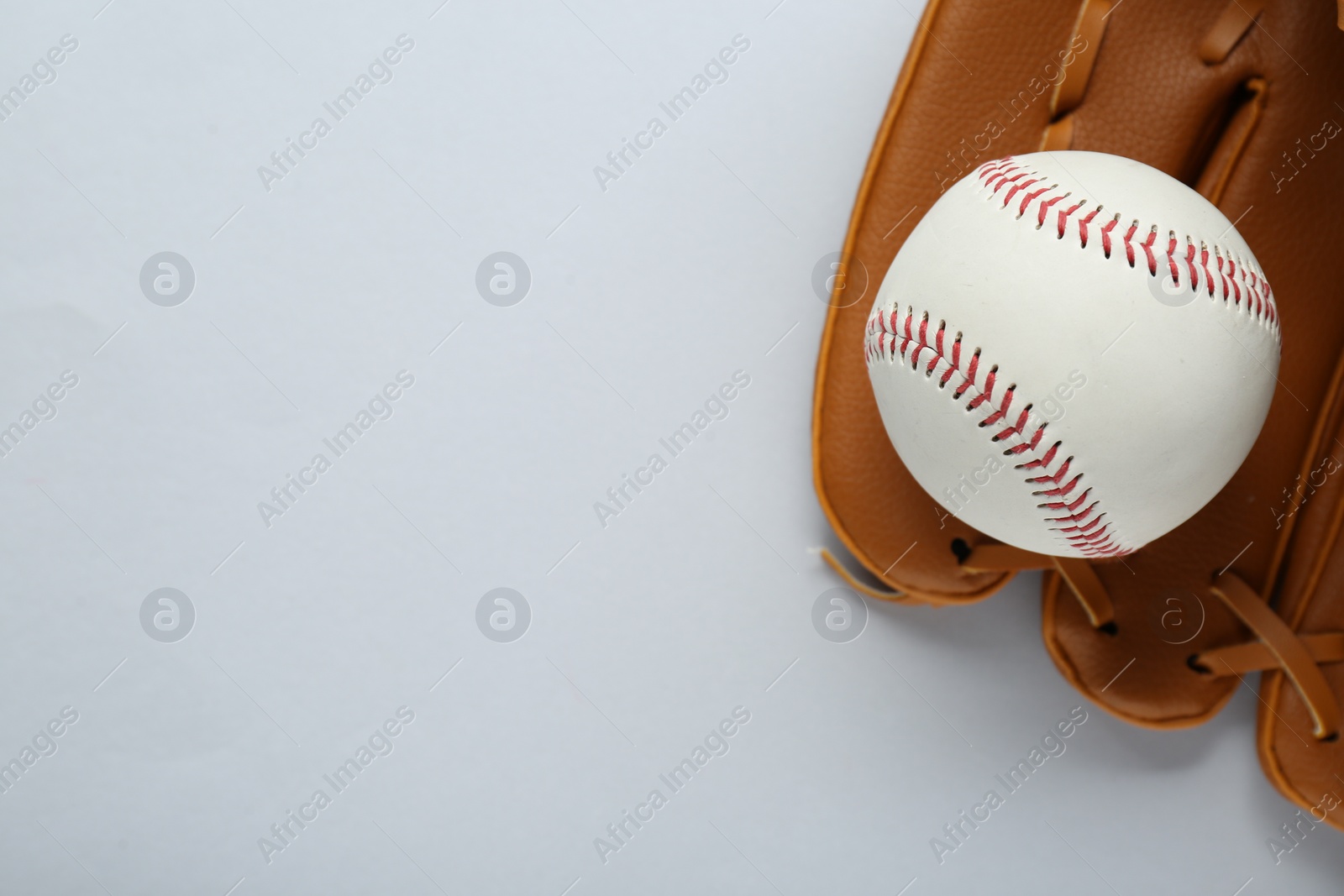 Photo of Catcher's mitt and baseball ball on white background, top view with space for text. Sports game