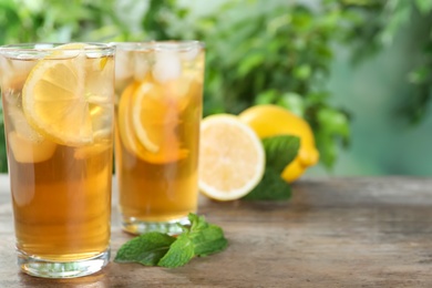 Photo of Delicious iced tea on wooden table outdoors, space for text