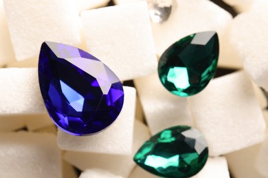 Different beautiful gemstones for jewelry on sugar cubes, closeup