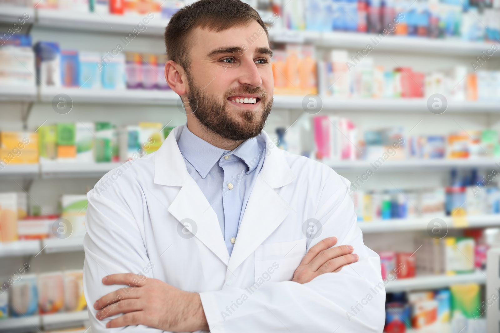 Photo of Professional pharmacist with crossed arms in modern drugstore