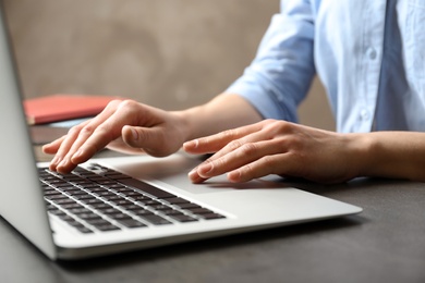 Photo of Woman using modern laptop at table, closeup