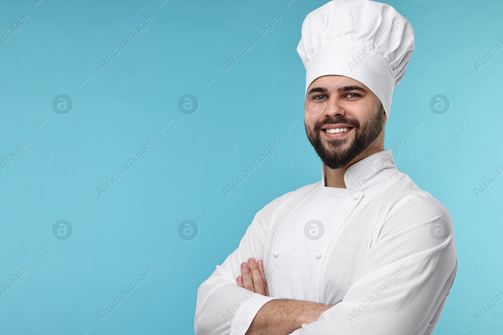 Photo of Happy young chef in uniform on light blue background. Space for text