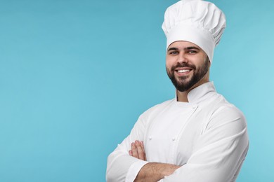 Happy young chef in uniform on light blue background. Space for text