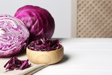 Whole and cut ripe red cabbages on white wooden table indoors. Space for text