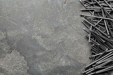 Photo of Pile of metal nails on grey stone background, flat lay. Space for text