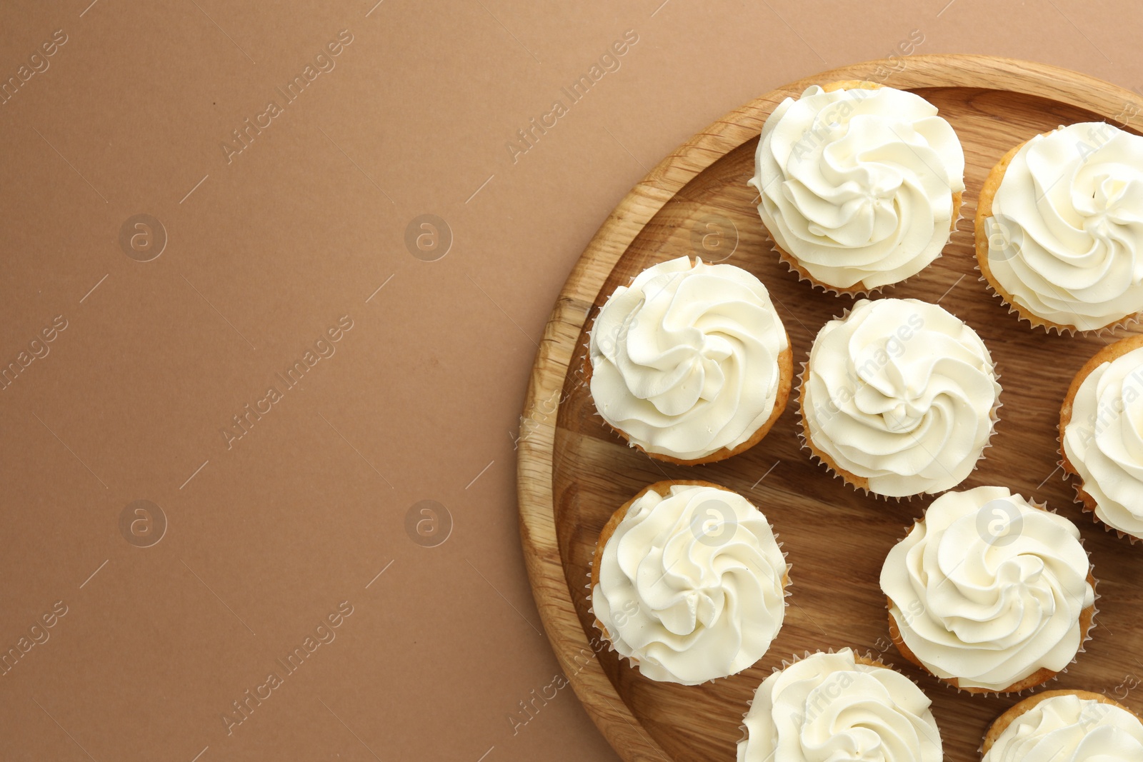 Photo of Tasty vanilla cupcakes with cream on dark beige background, top view. Space for text