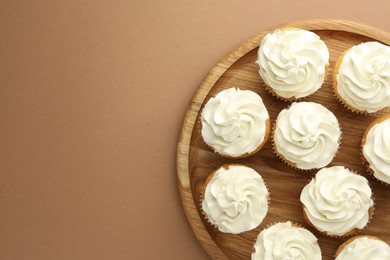 Photo of Tasty vanilla cupcakes with cream on dark beige background, top view. Space for text