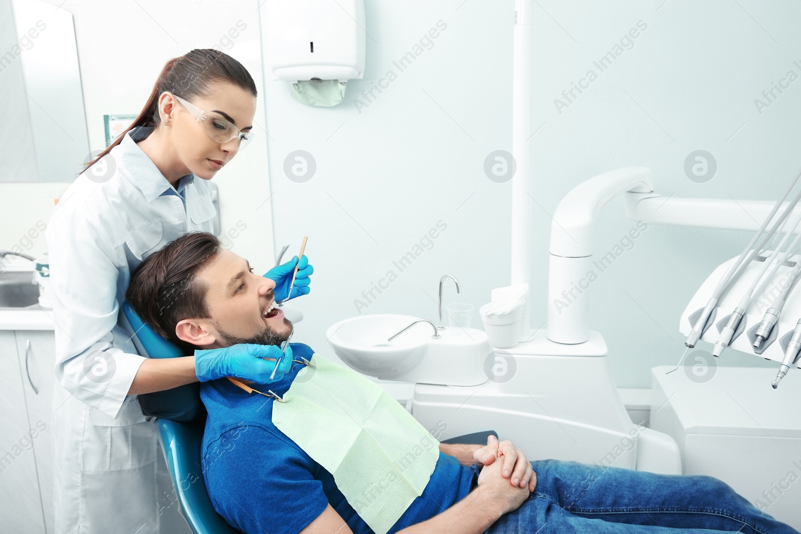 Photo of Professional dentist working with patient in modern clinic. Space for text