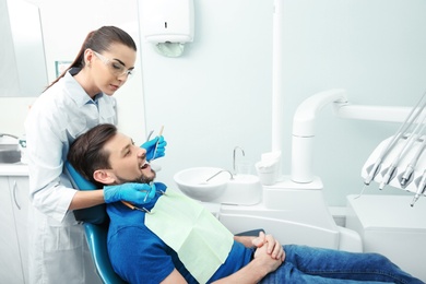 Professional dentist working with patient in modern clinic. Space for text