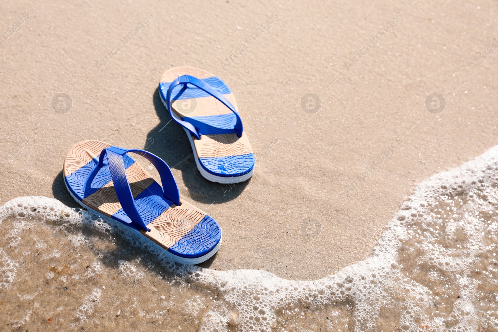 Photo of Stylish flip flops on beach. Space for text