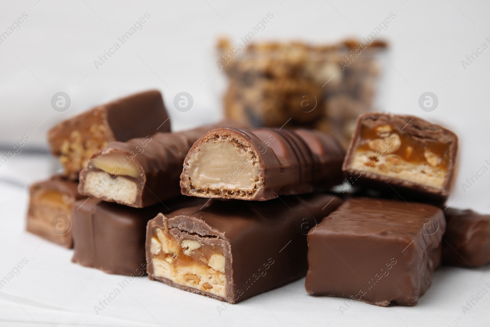 Photo of Pieces of different tasty chocolate bars on white table, closeup