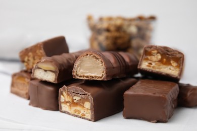 Photo of Pieces of different tasty chocolate bars on white table, closeup