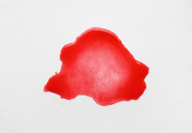 Photo of Blot of red ink on white background, top view