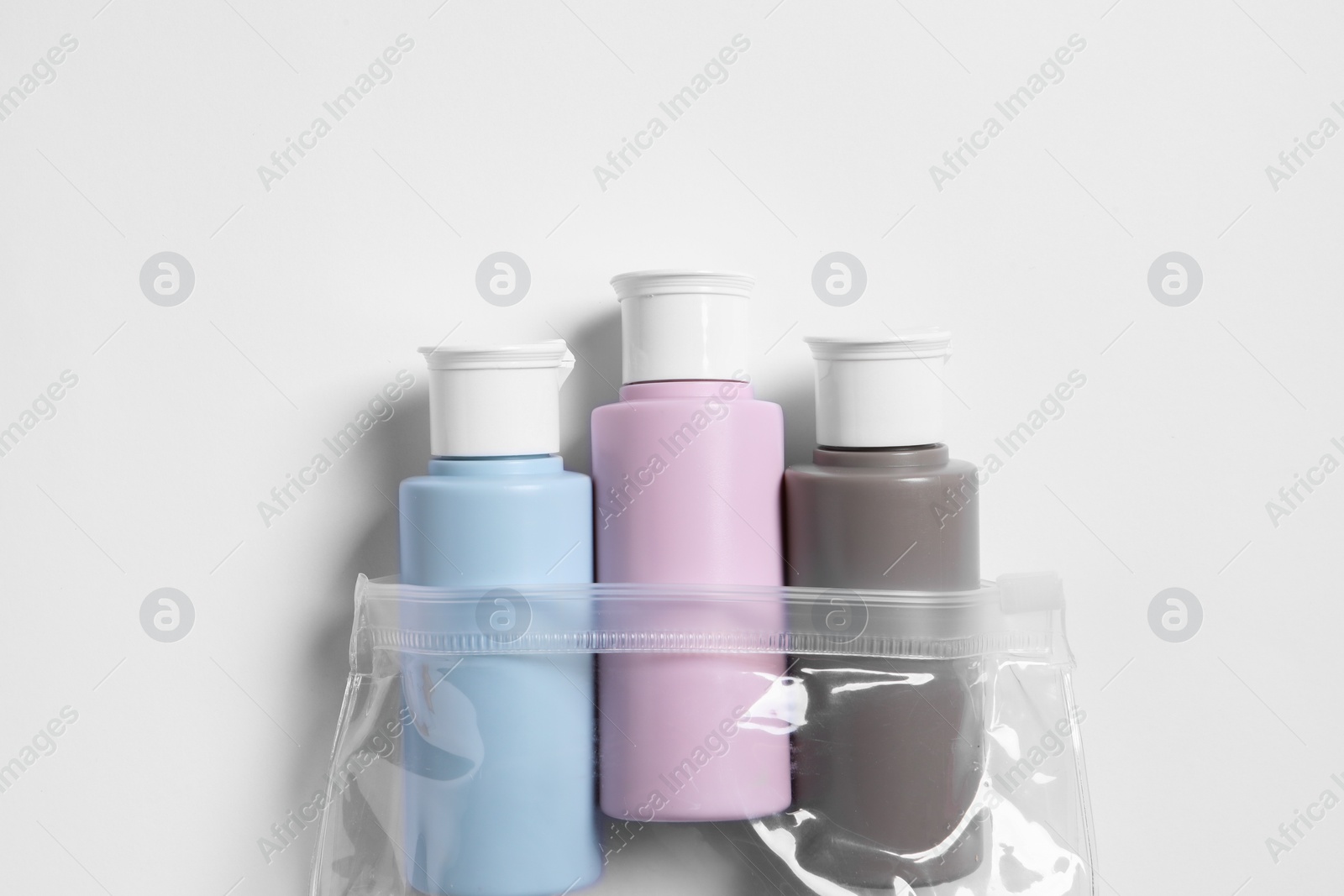 Photo of Cosmetic travel kit in plastic bag on white background, top view