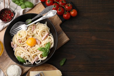 Photo of Delicious pasta Carbonara with egg yolk on wooden table, flat lay. Space for text