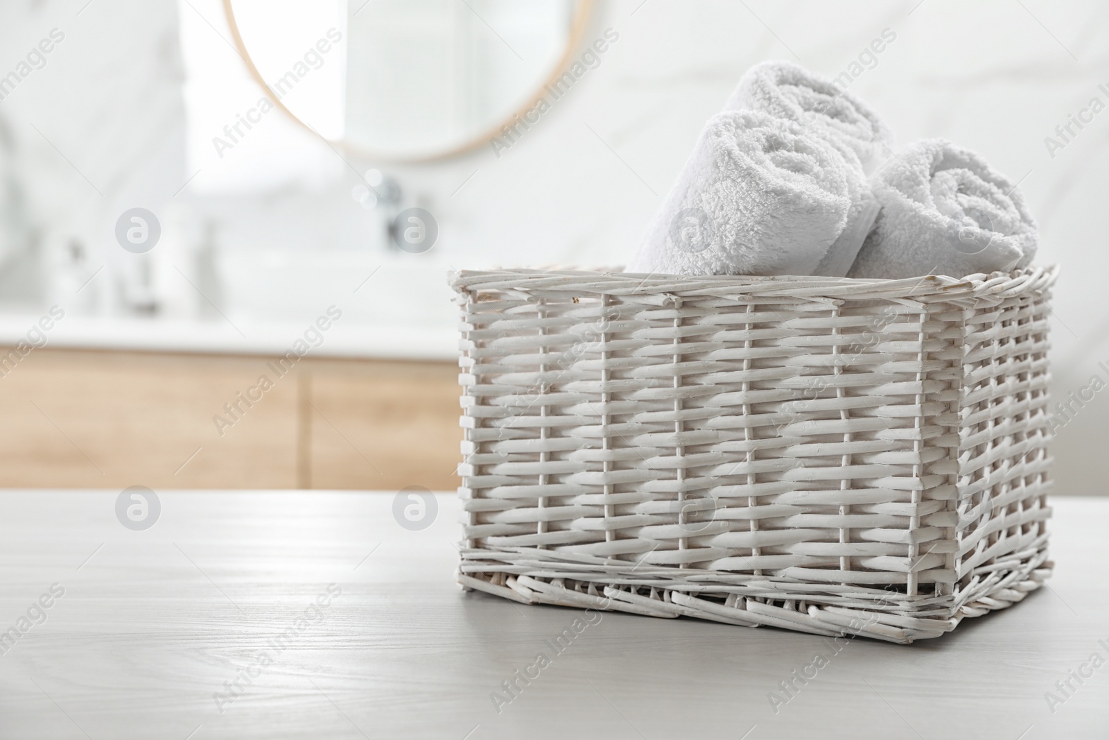 Photo of Rolled fresh towels on white table in bathroom