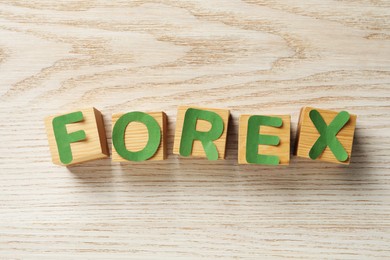Word Forex made of green letters and cubes on wooden table, flat lay