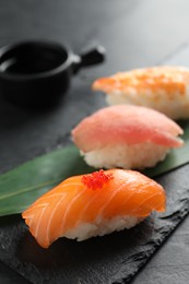 Serving board with delicious nigiri sushi and soy sauce on black table, closeup