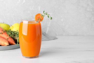 Glass with healthy carrot juice and ingredients on white table. Space for text