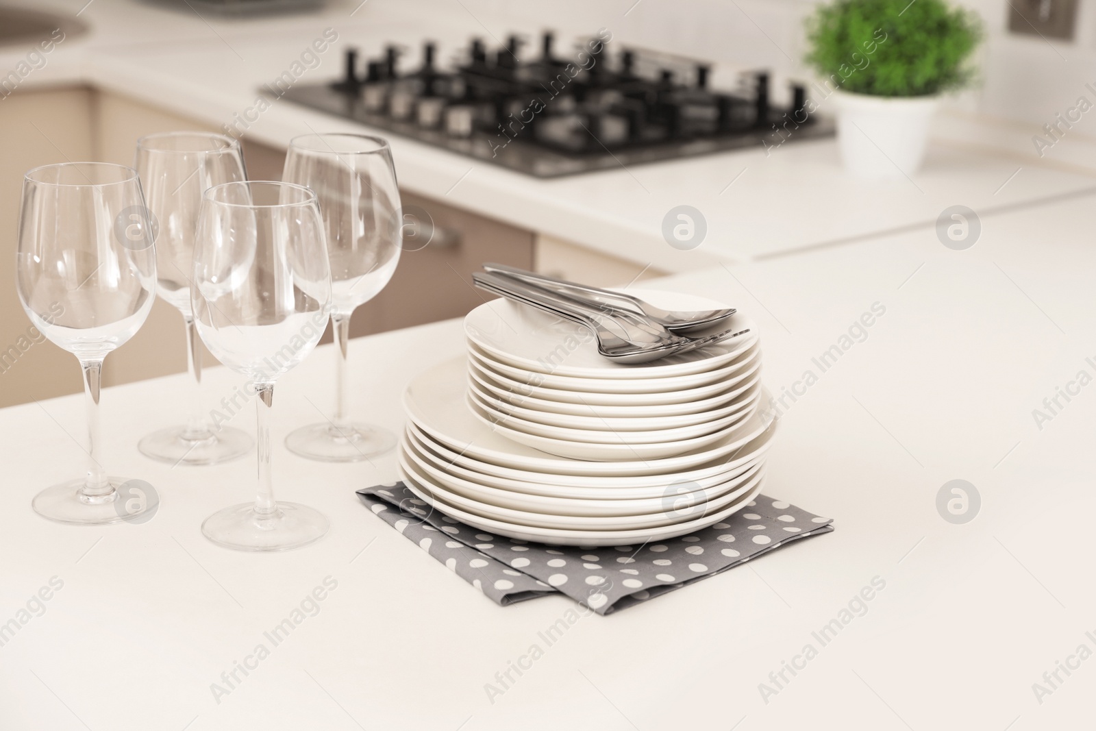 Photo of Stack of clean dishes and glasses on table in kitchen