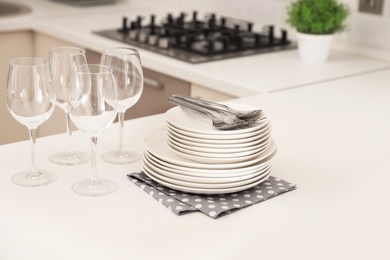 Photo of Stack of clean dishes and glasses on table in kitchen