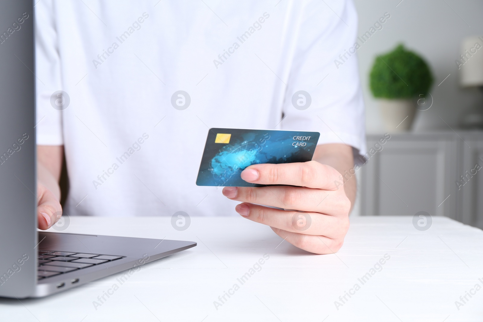 Photo of Online payment. Woman with laptop and credit card at white table, closeup