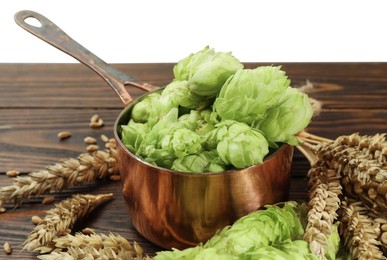 Photo of Fresh hop flowers and wheat ears on wooden table against white background, closeup