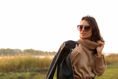 Photo of Beautiful young woman wearing stylish autumn clothes outdoors