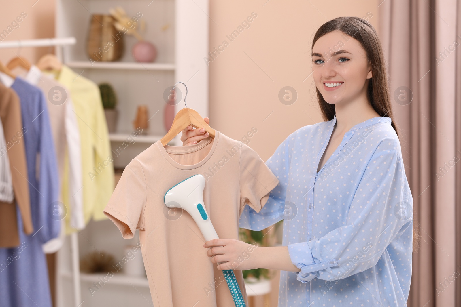 Photo of Woman steaming shirt on hanger at home