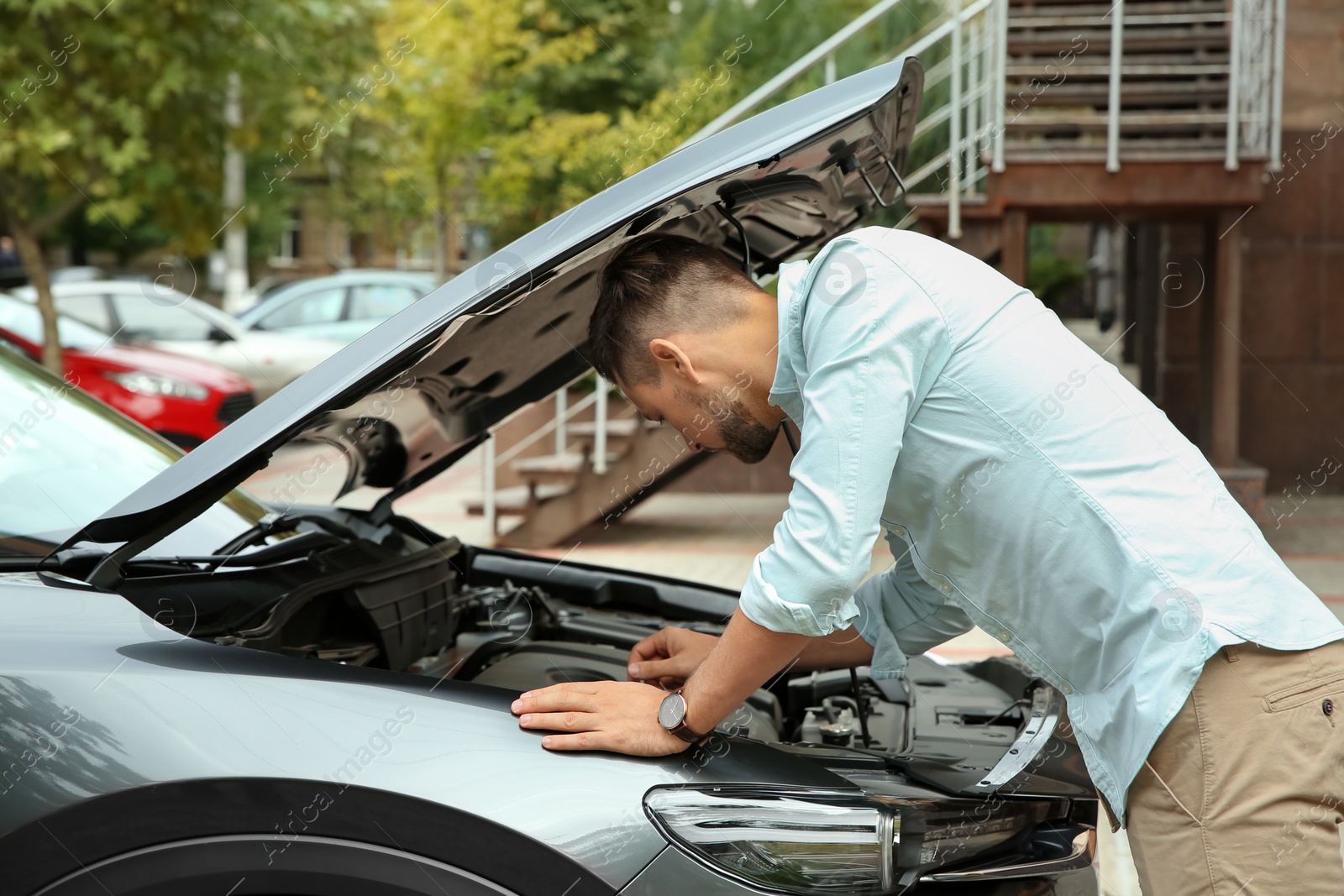 Photo of Man fixing broken car on city street