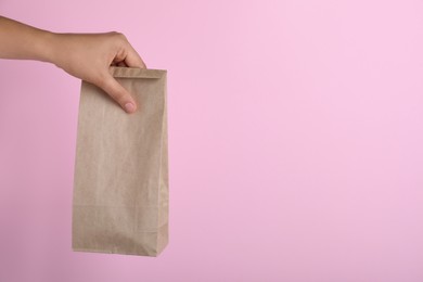 Photo of Woman holding paper bag on pink background, closeup. Space for text