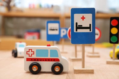 Photo of Different miniature road signs and cars on wooden table, closeup. Montessori toy