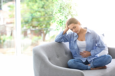 Young woman suffering from menstrual cramps at home. Gynecology