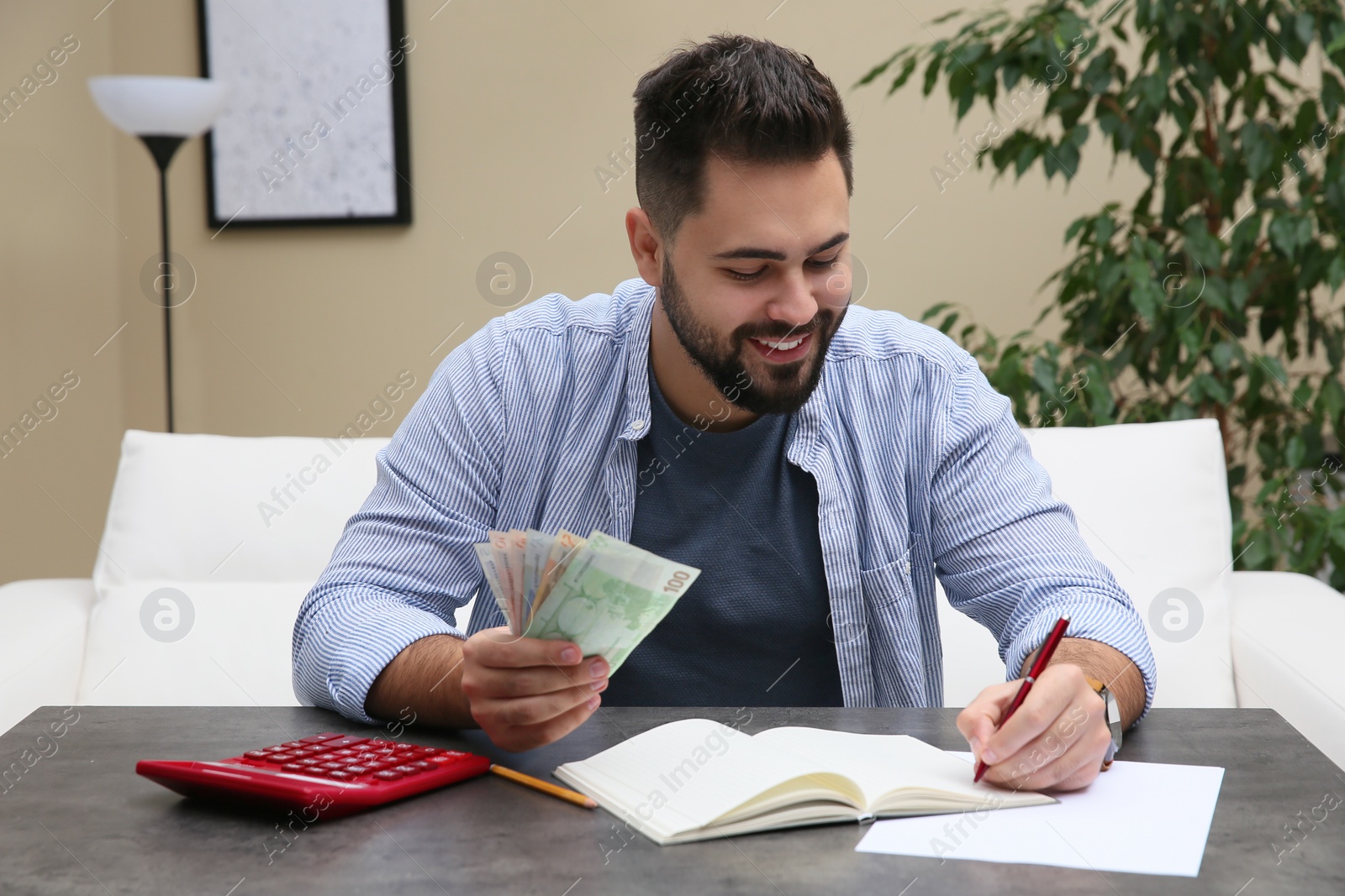 Photo of Young man with money at table indoors