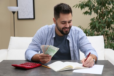 Photo of Young man with money at table indoors