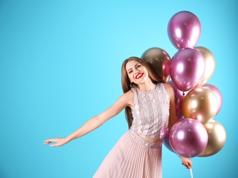 Photo of Young woman with air balloons on color background