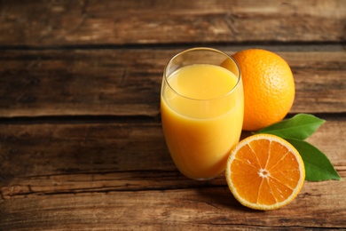 Glass of orange juice and fresh fruits on wooden table. Space for text