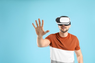 Photo of Man using virtual reality headset on light blue background