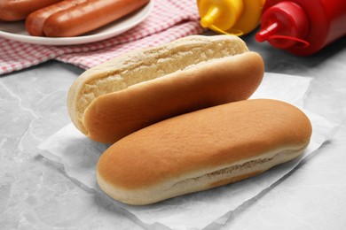 Tasty fresh buns and different ingredients for hot dog on light grey marble table, closeup