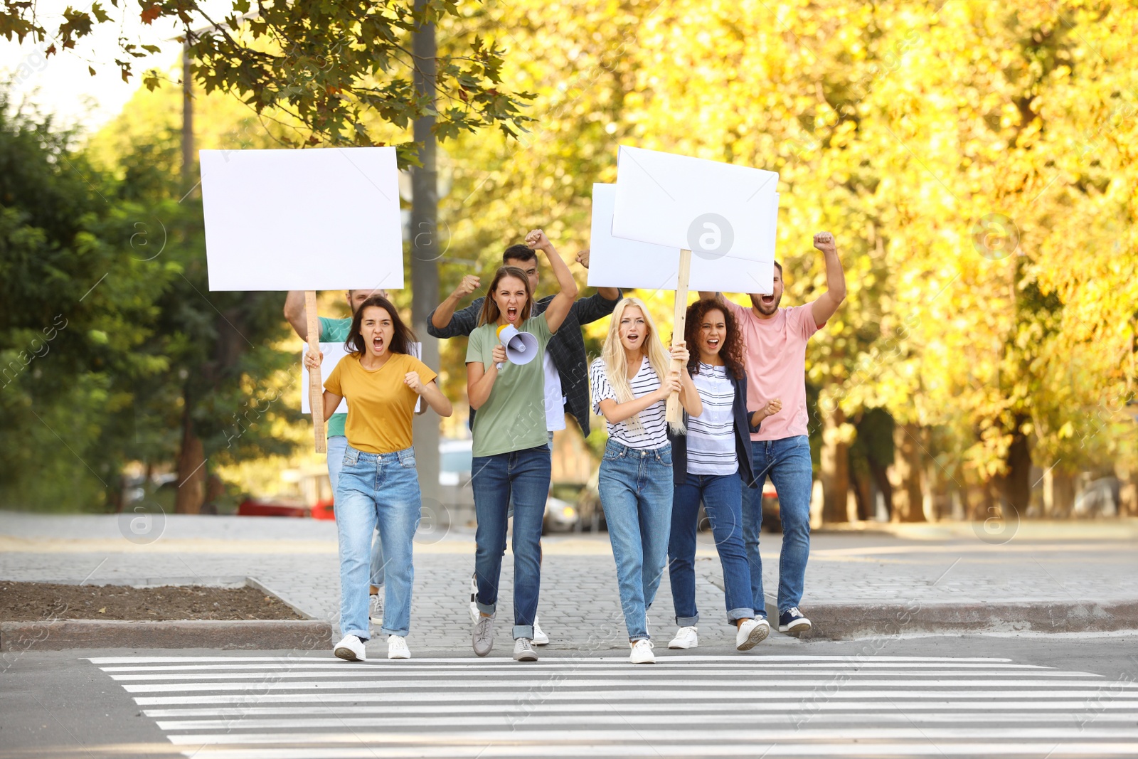 Photo of Emotional young woman with megaphone leading demonstration outdoors