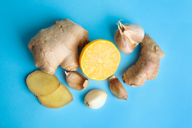 Photo of Fresh garlic and other natural cold remedies on light blue background, flat lay