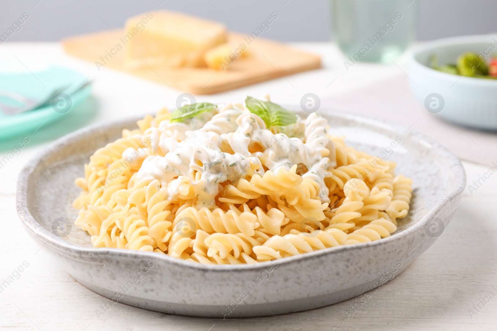 Photo of Tasty pasta with sauce and basil on white wooden table, closeup