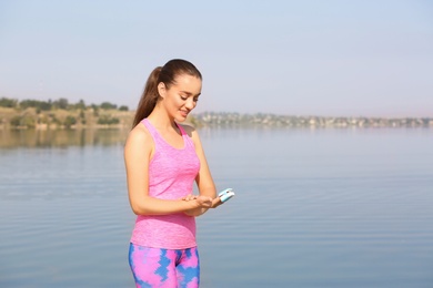 Photo of Young woman checking pulse outdoors on sunny day