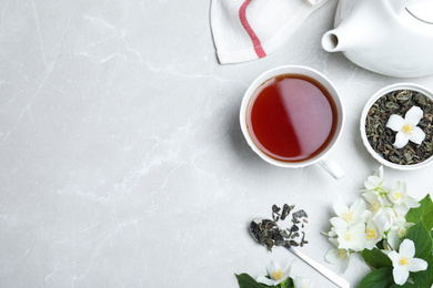 Photo of Flat lay composition with tea and fresh jasmine flowers on light grey marble table. Space for text