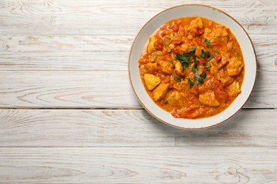 Photo of Delicious chicken curry on wooden table, top view. Space for text