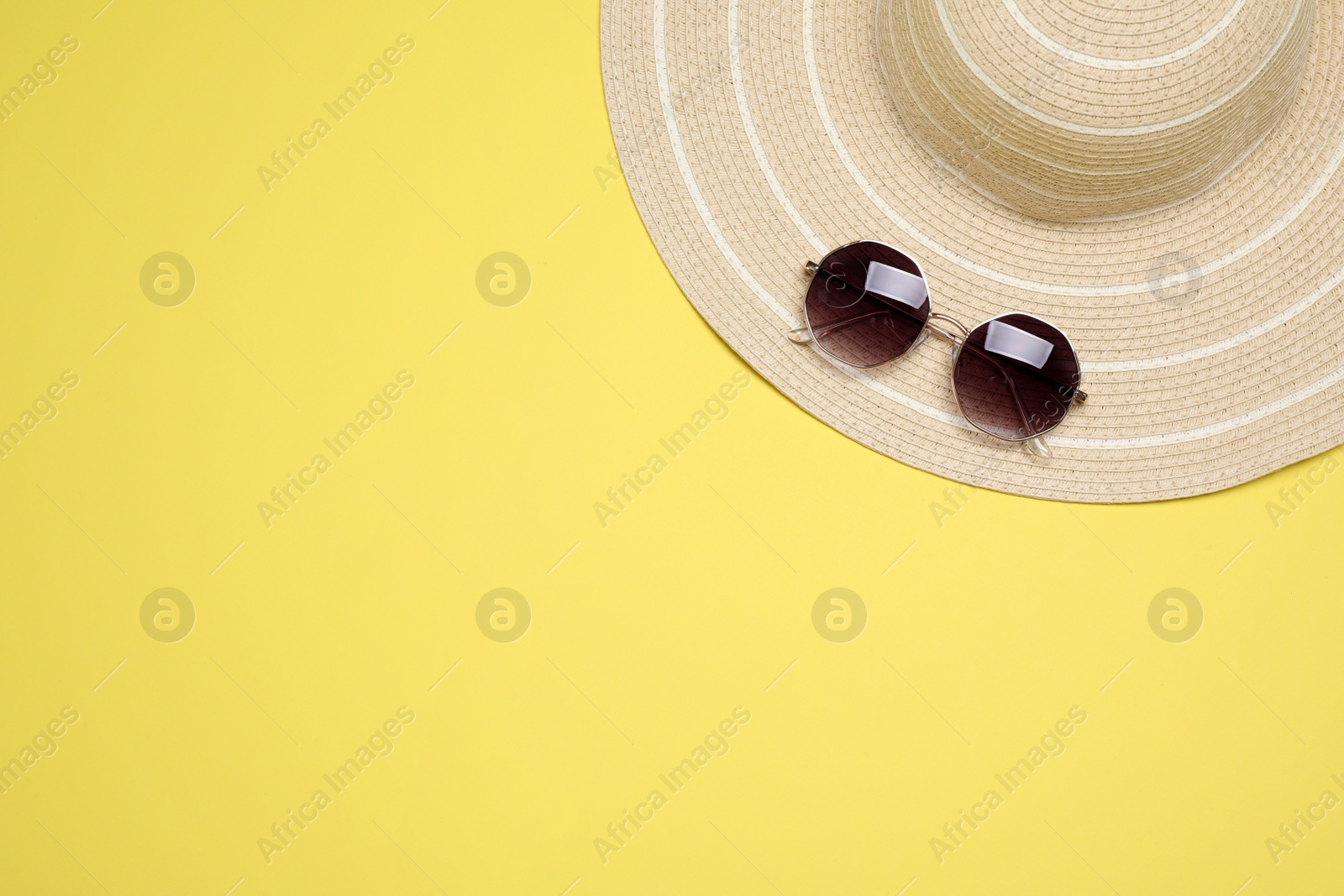 Photo of Hat and sunglasses on yellow background, top view with space for text. Beach objects