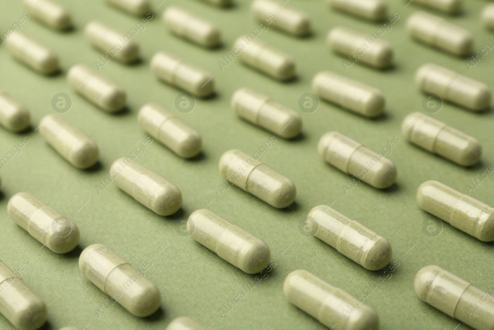 Photo of Many vitamin capsules on olive background, closeup